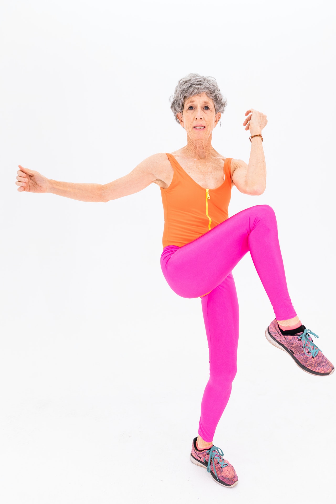 a woman in pink leggings and orange top doing a dance