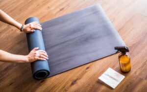 a person rolling out a yoga mat on a wooden floor